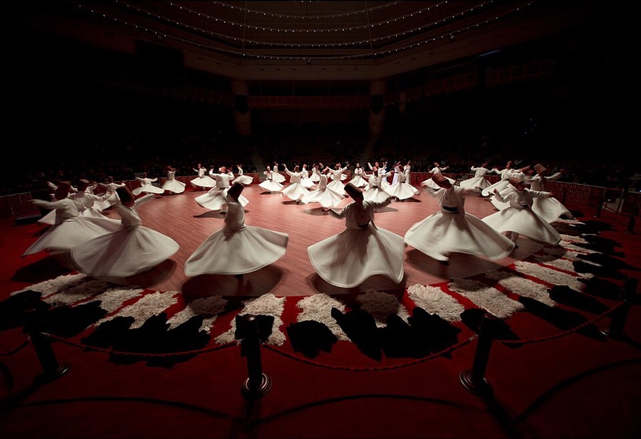 Mevlevi sema performers whirling in a modern hall